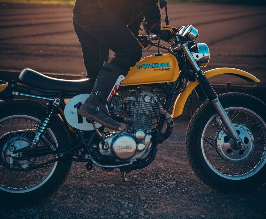 Un motociclista intenta arrancar su moto amarilla con una patada
