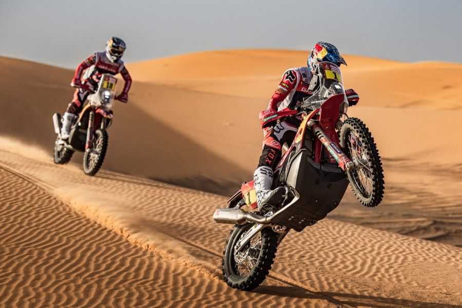 una moto hace un caballito sobre la arena durante el rally dakar