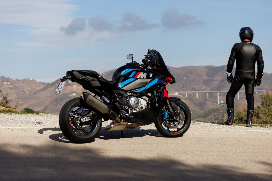 Un piloto y una moto BMW M 1000 XR posan al borde de una acantilado 