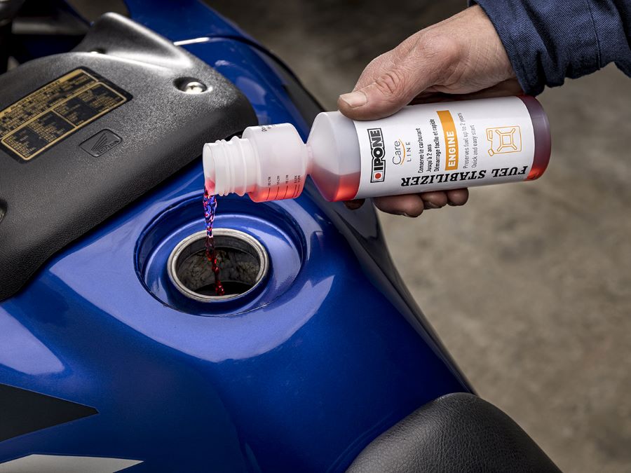 Aditivos para gasolina en motos 4 tiempos | ¿Cuáles sirven? Una mano echa aditivo en un tanque de moto
