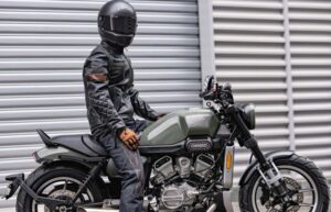 Un usuario, con casco negro, posa sobre una moto cruiser Hyosung GV250X Roadster
