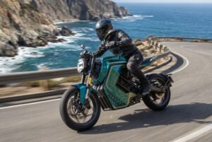 Una moto eléctrica Charged Ndara transita por una ruta que bordea el mar