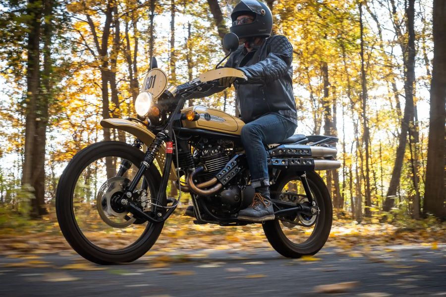 Un motociclista se traslada co una moto Janus por un bosque otoñal