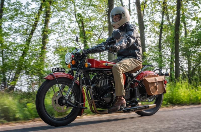 Un motociclista se deplaza por una ruta arbolada con una janus halcyon 450 Origin