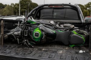 Una moto Kawasaki recostada transversalmente sobre la caja de una camioneta