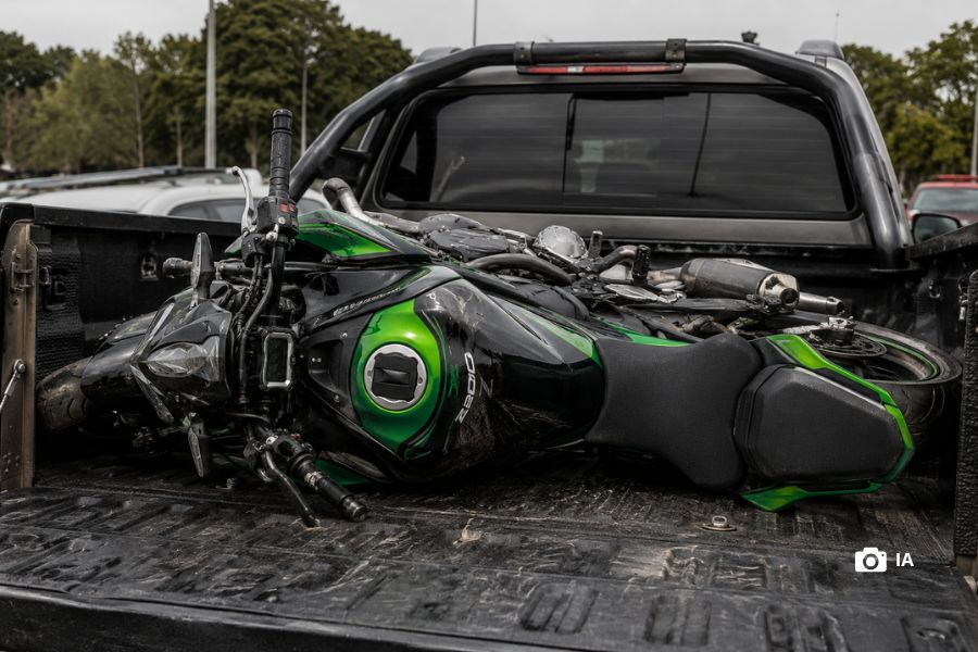 Una moto Kawasaki recostada transversalmente sobre la caja de una camioneta