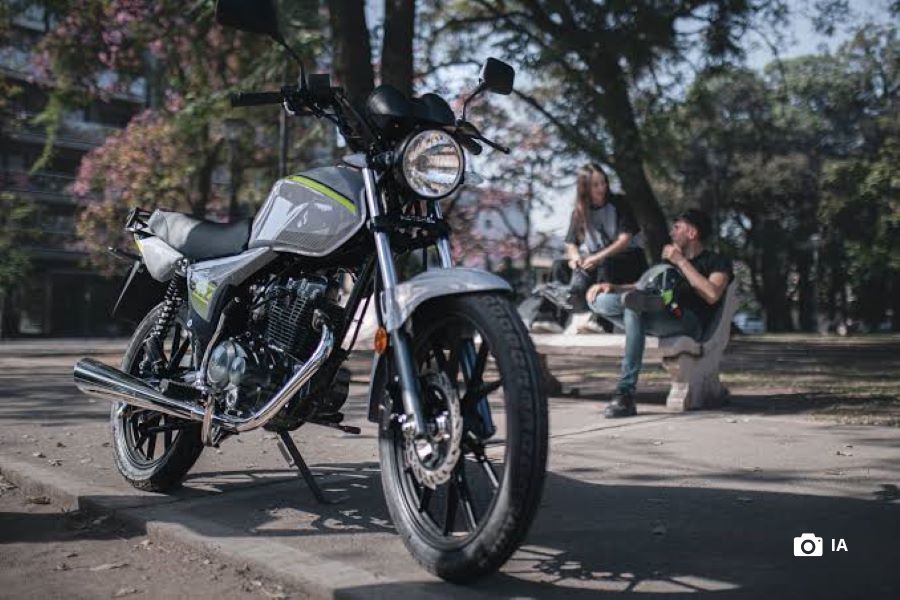 Consumo de la Motomel S2 ¿Cuánto gasta y cuánto rinde? en primer plano, una Motomel s2 gris, al fondo una pareja de adolescentes