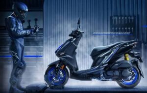 Un piloto posa al frente de un scooter Yamaha Cygnus X edición especial en medio del humo