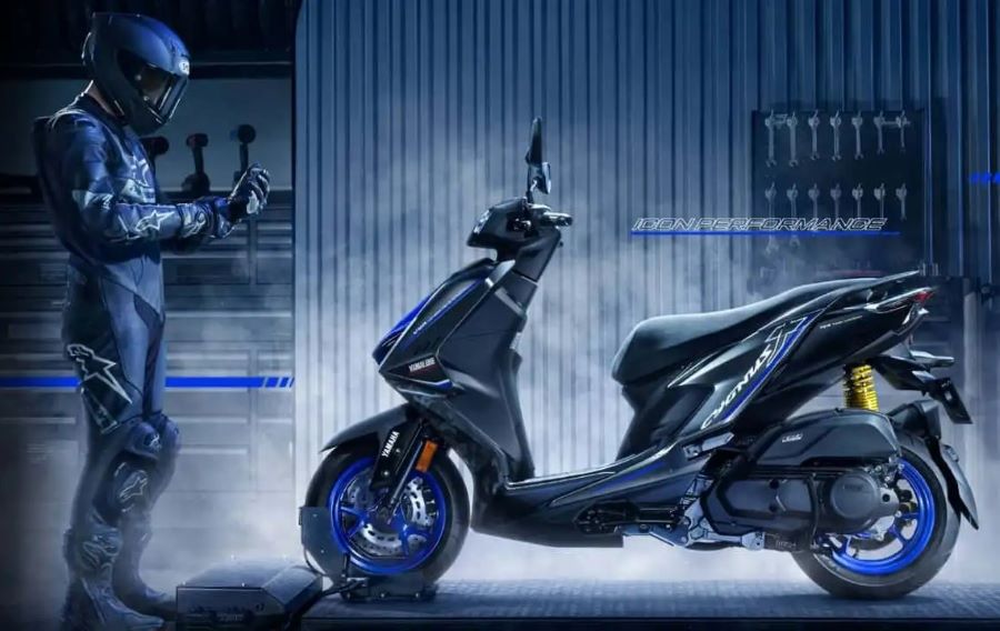 Un piloto posa al frente de un scooter Yamaha Cygnus X edición especial en medio del humo