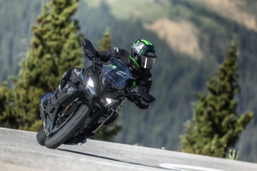 Una Kawasaki Ninja 1100SX 2027 avanza en la carretera con las luces encendidas.