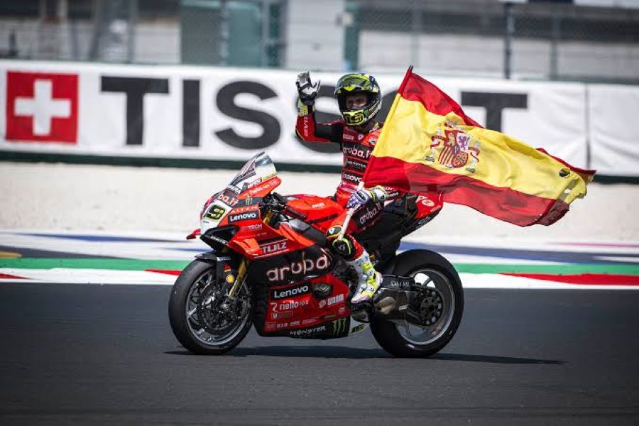 Álvaro Bautista se desplaza con su Ducati, portando una bandera española, luego de obtener una victoria