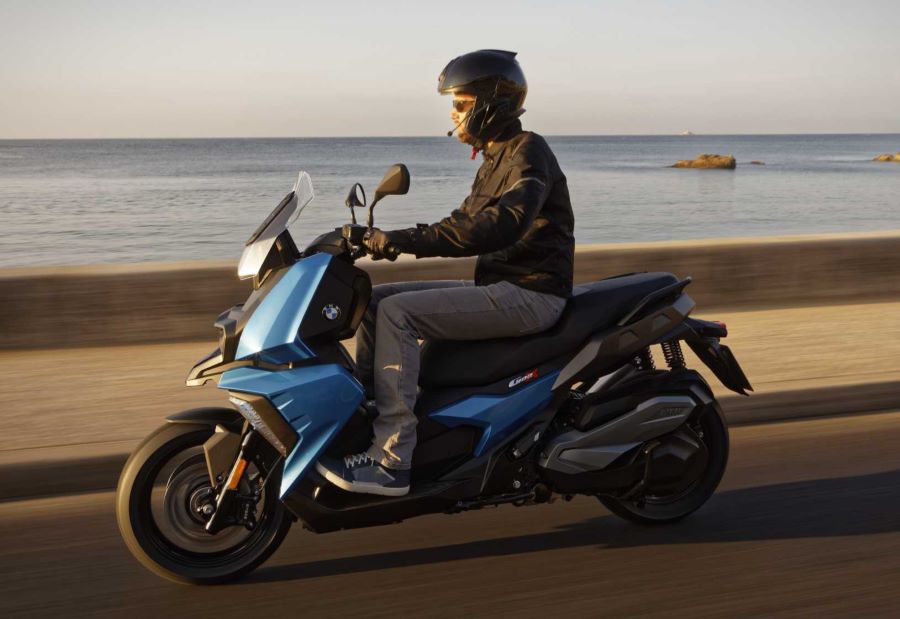 Cinco formas de entender el scooter crossover moderno Un piloto viaja con su BMW C 400 X a la vera del mar