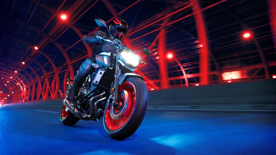 Una Yamaha MT 15 atraviesa un puente de hierro rojo durante la noche