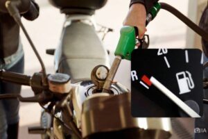 una moto repostando gasolina. Esquina inferior derecha, un tablero muestra la reserva de combustible