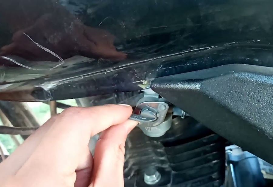 una mano manipula la llave de paso de gasolina de una moto