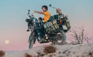 Agustín Ostos, subido a su moto cargada de equipaje, señala un punto a su izquierda