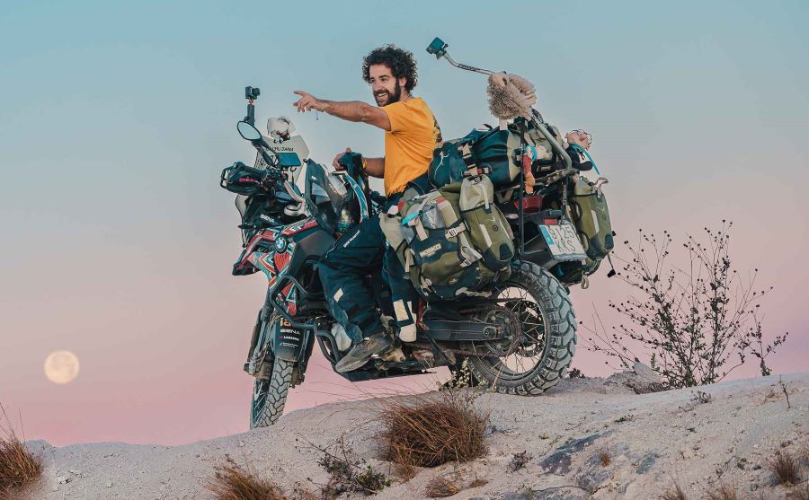 Agustín Ostos, subido a su moto cargada de equipaje, señala un punto a su izquierda