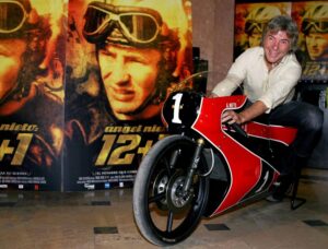 Ángel Nieto sonríe a la cámara sentado sobre una moto roja con el número 1