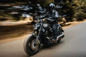 Una moto Benda Dark Flag 600 V4 avanza en una carretera arbolada