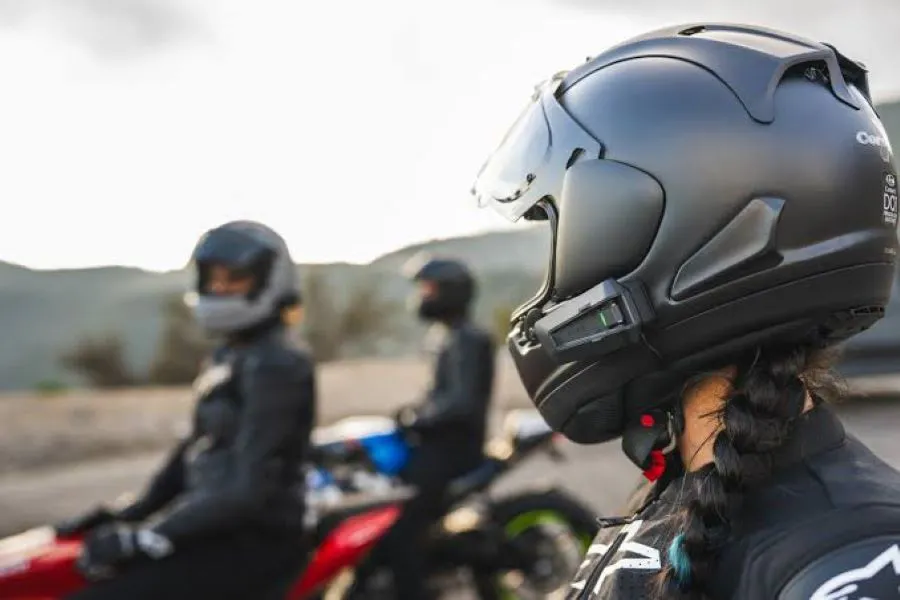 En primer plano una motorista con casco con intercomunicador Cardo Mesh