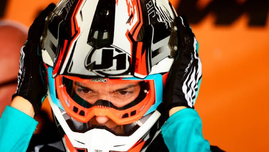 Un piloto de motocross se ajusta el casco con ambas manos