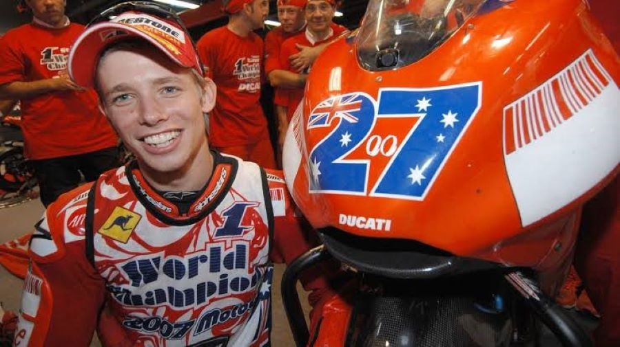 Medio cuerpo de Casey Stoner al lado de su Ducati con el característico número 27