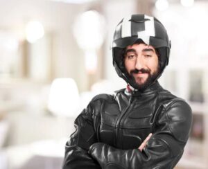 Un motociclista con cara muy particular y media sonrisa mira a la cámara con el casco puesto