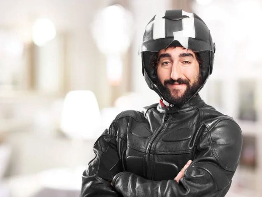 Un motociclista con cara muy particular y media sonrisa mira a la cámara con el casco puesto