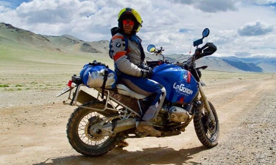 Miquel silvestre sobre su conocida moto BMW azul en un camino desértico