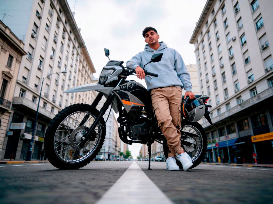 Un joven modelo se apoya en una moto Corven Triax 200 Max 2026 negra