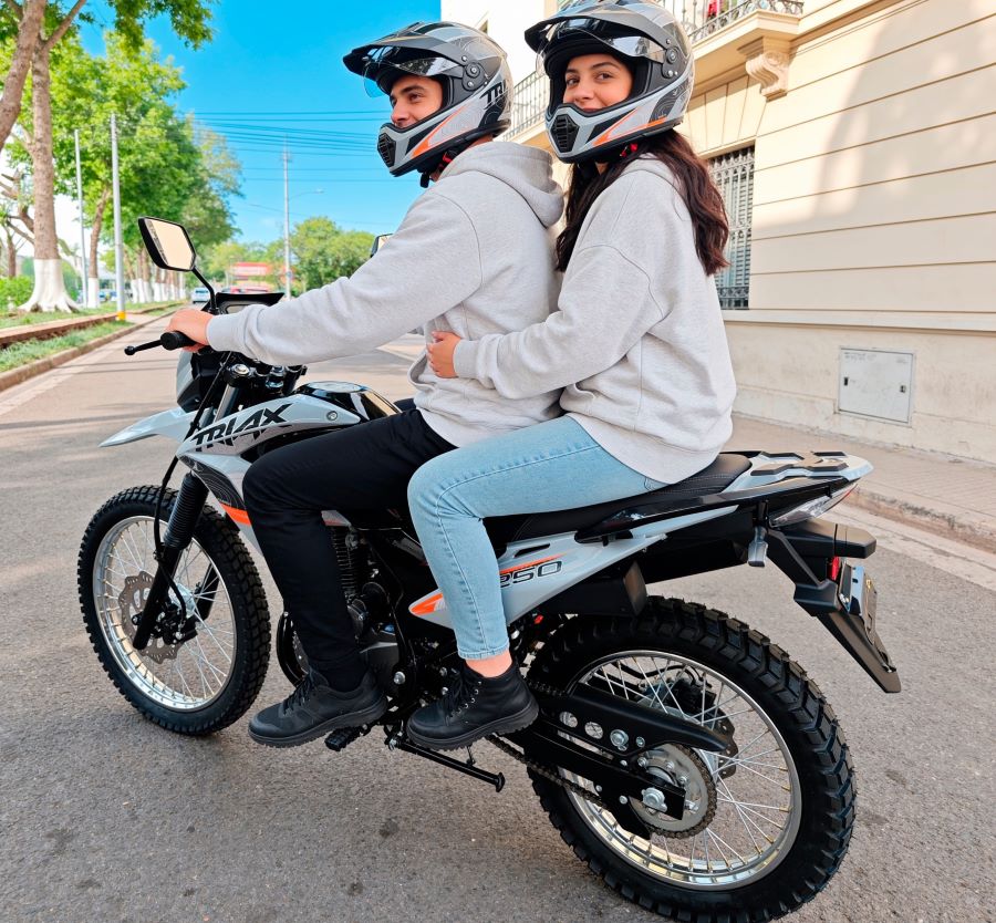 Una pareja mira a la cámara subida a una moto Corven Triax 250 Max 2026