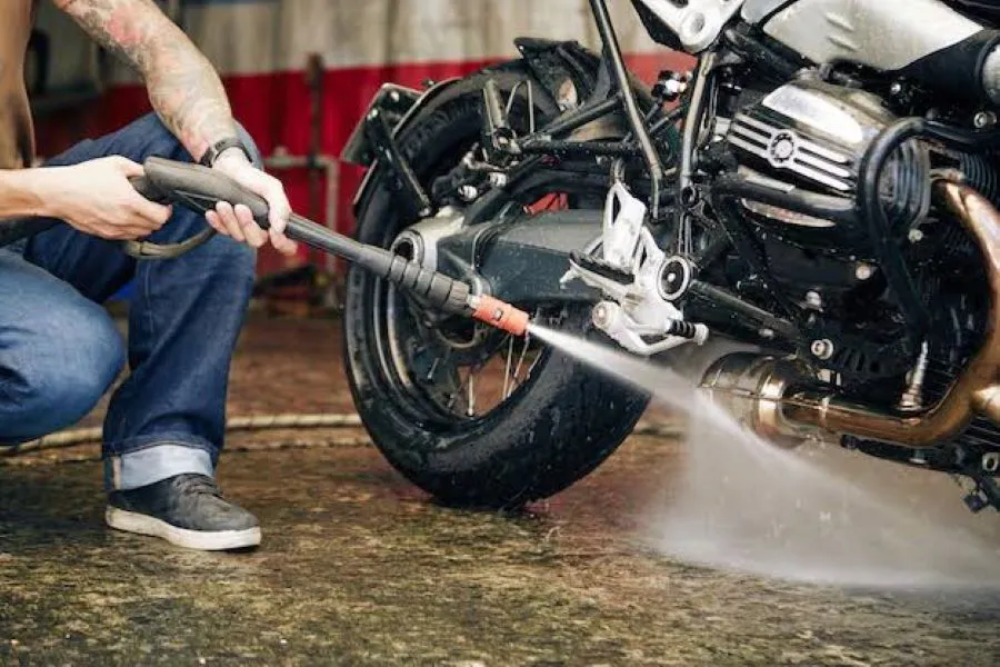 Una persona apunta el chorro de agua de una hidrolavadora hacia una moto