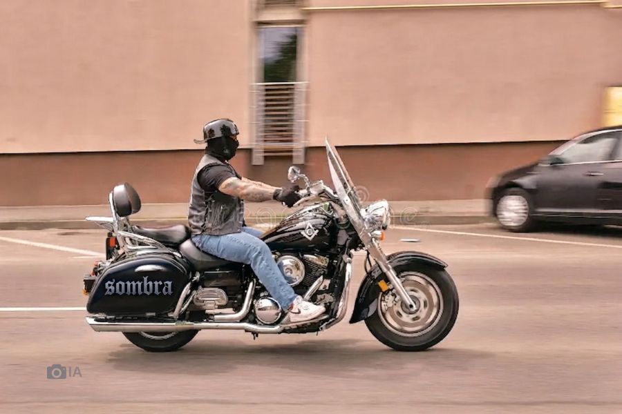 Un notociclista se desplaza en una moto custom negra con la leyenda "sombra" en la maleta trasera