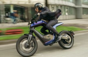 Un motociclista circula con una moto eléctrica Novus One azul por una calle de ciudad