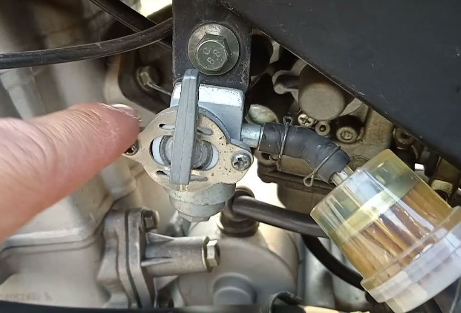 Un dedo señala la llave de paso de gasolina de una moto