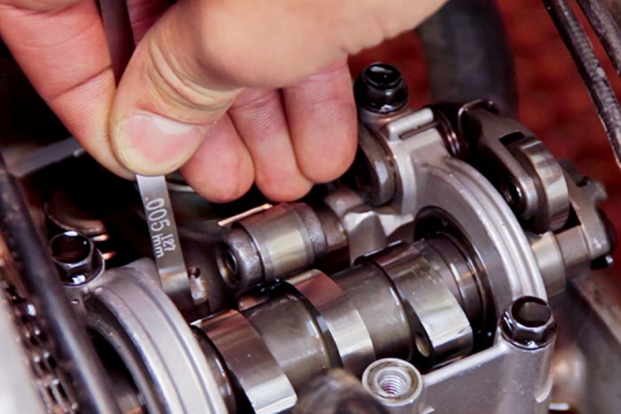 Un mecánico mide el reglaje de las válvulas del motor de una moto