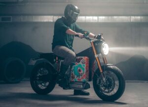 Un usuario se sienta sobre una moto Blacksheep one con las luces encendidas