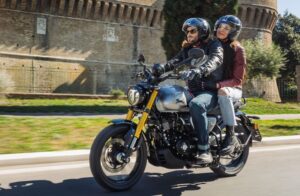 Una pareja se desplaza por la ciudad con una moto TVS Ronin 250 gris