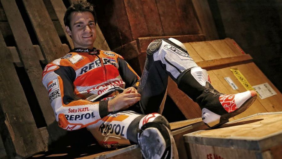 Dani Pedrosa sonríe sentado sobre unos pallets y con su mono puesto
