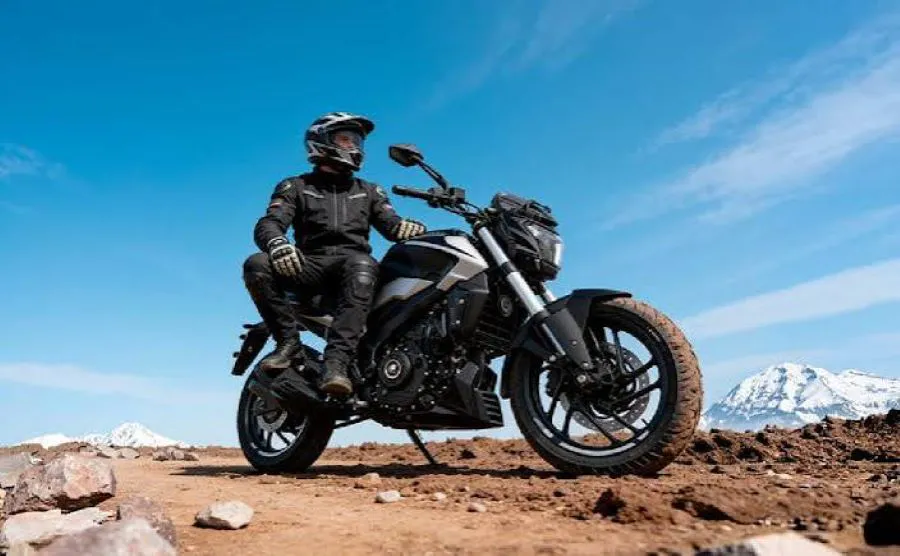 Un usuario de la Bajaj Dominar 250 UG2 mira a lo lejos sentado sobre su montura