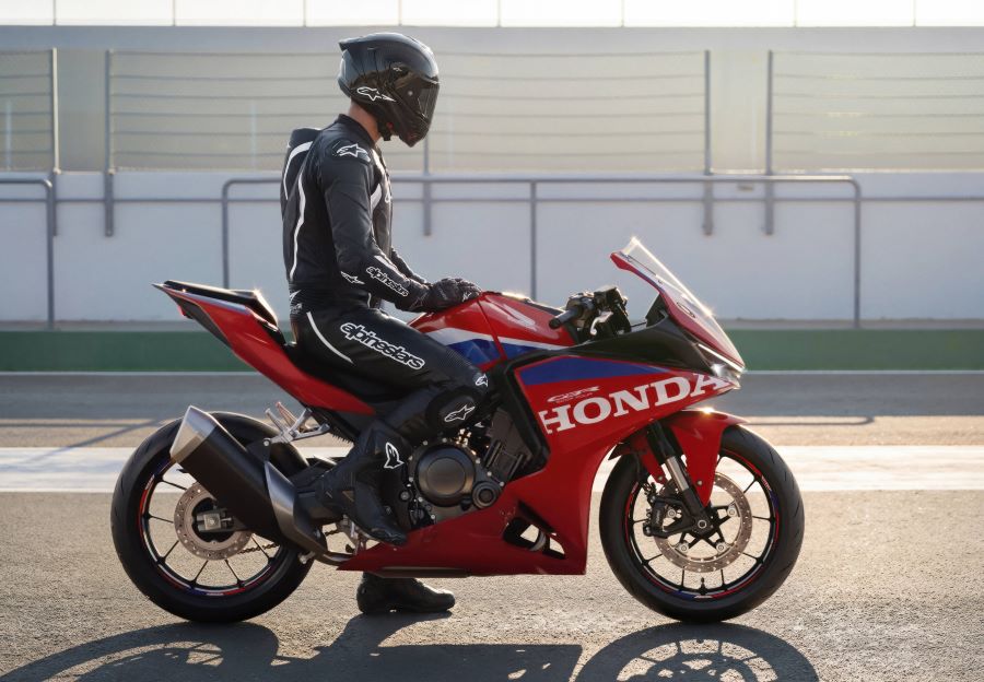 Un piloto, pie en el piso, descansa sobre una Honda CBR500R FOUR