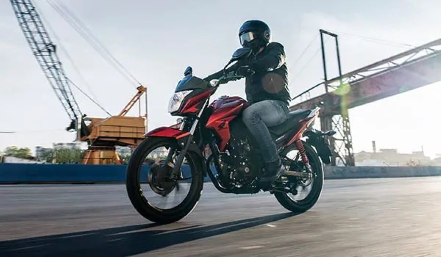 Una Honda Twister 125 roja se desplaza por una zona portuaria