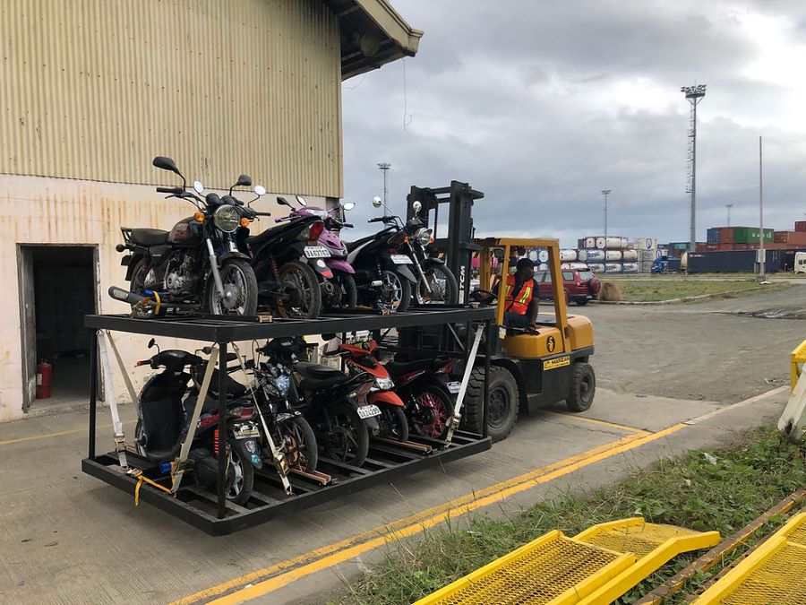 Un carrito transporta varias motos usadas en un sector de un puerto