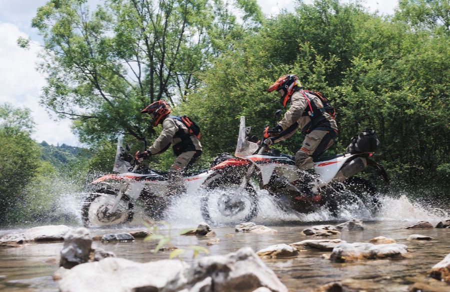 Dos KTM 690 Rally 2027 cruzan el lecho de una arroyo de manera transversal