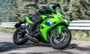 Lateral derecho de una Kawasaki Ninja 650 2027 verde circulando en una carretera contra el guarda rail