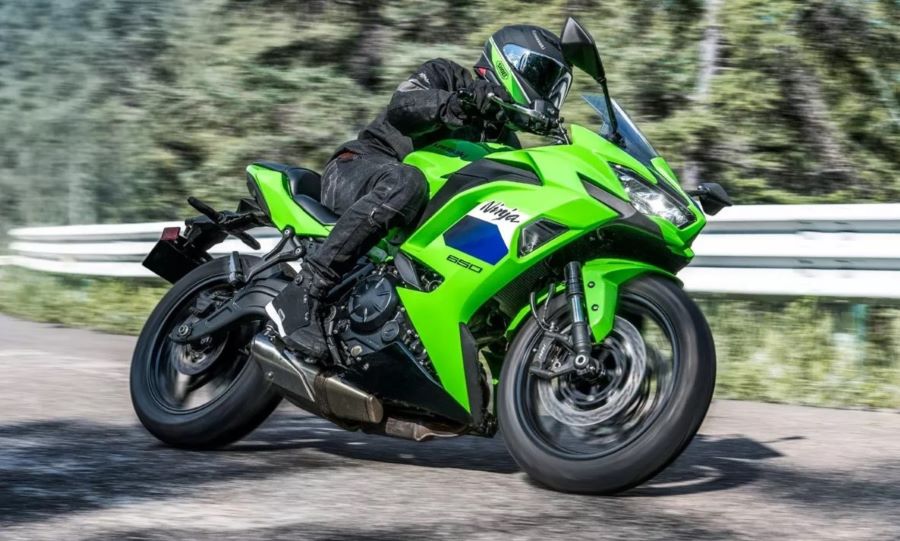 Lateral derecho de una Kawasaki Ninja 650 2027 verde circulando en una carretera contra el guarda rail