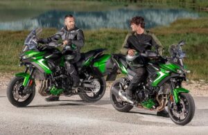 Dos usuarios conversas sentados en sendas Kawasaki Versys 900 2027 verdes en medio de la naturaleza