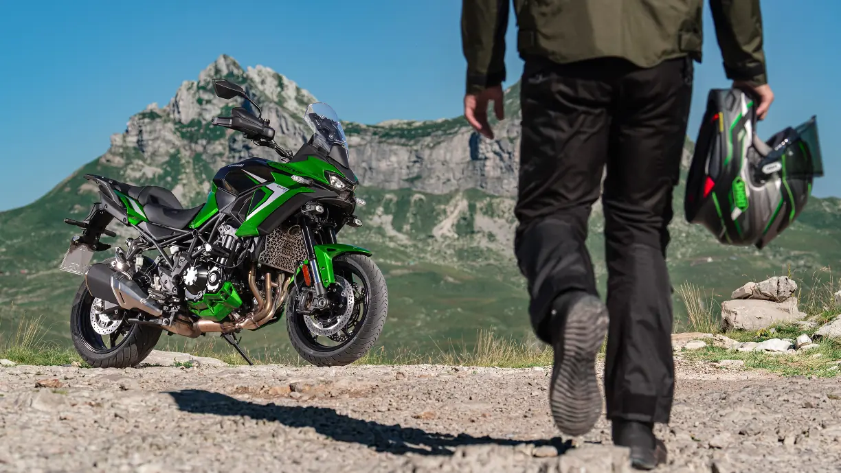 Una usuario, casco en mano, se acerca a una Kawasaki Versys 900 2027 verde