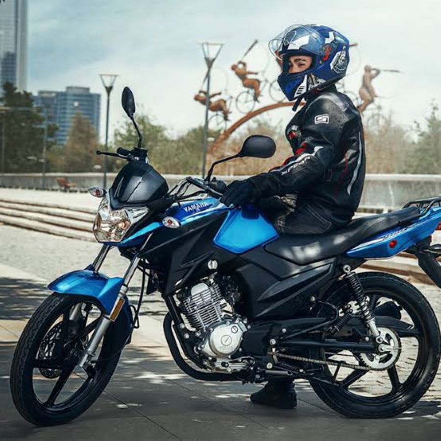 Un piloto sentado sobre una moto Yamaha YBR 125 azul