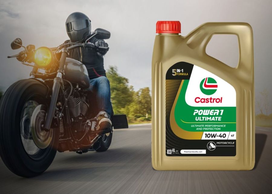 Una moto custom acompañada por un envase de aceite Castrol para moto